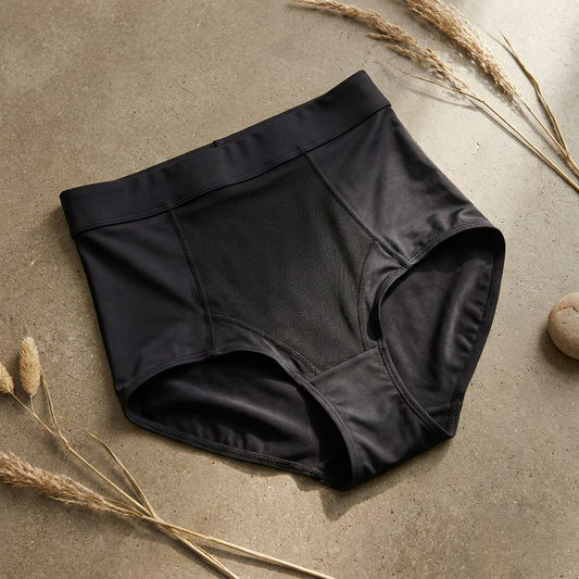 Shaping-Slip in Schwarz mit hoher Taille, breitem Bund und verstärkter Vorderpartie auf grauem Beton